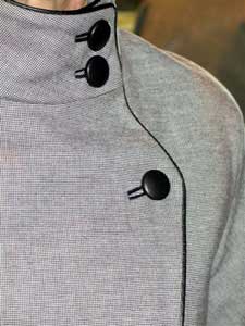Black leather piping, buttonholes and buttons create stunning design lines and focal points on this 2 piece suit.